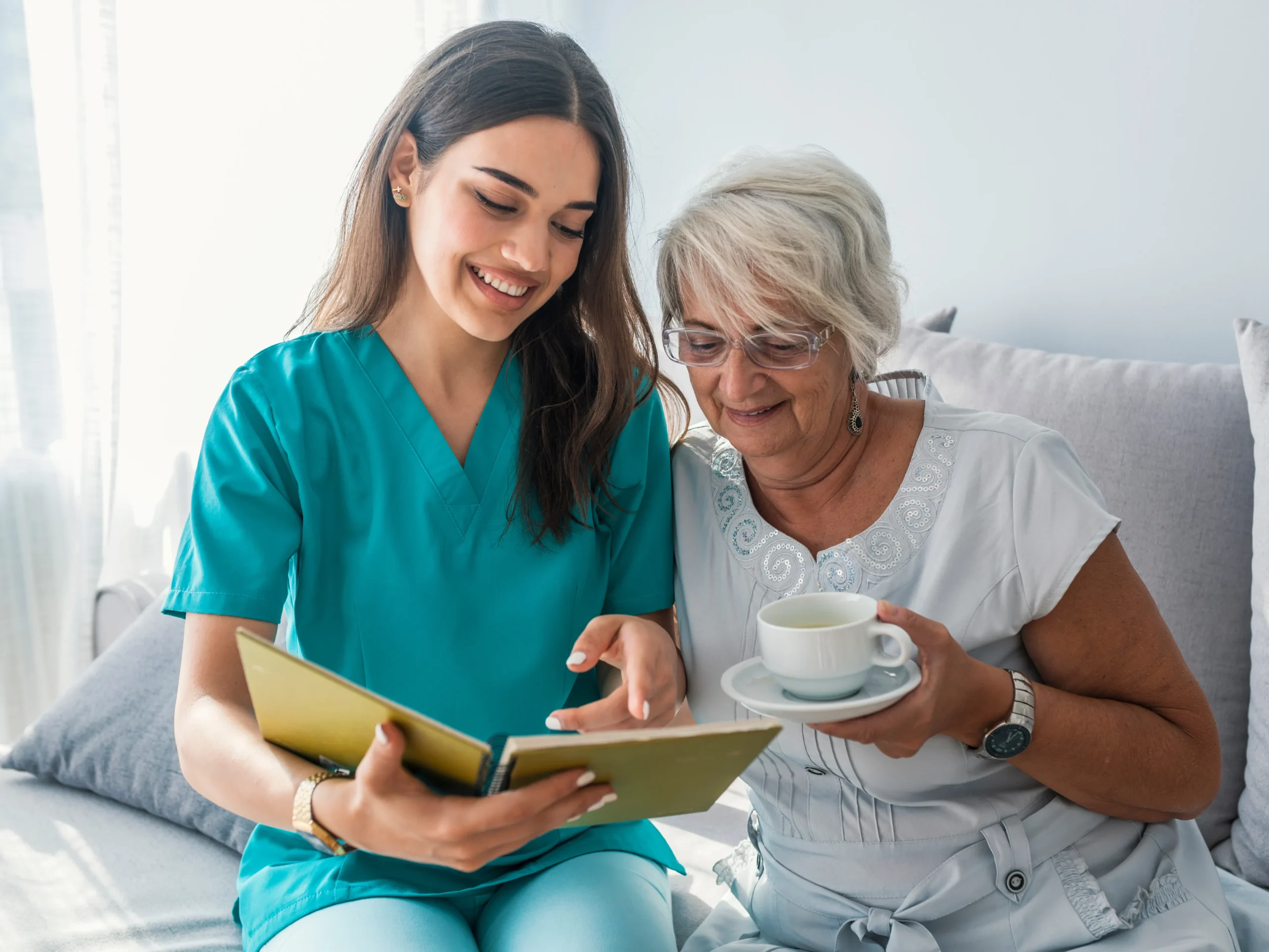 caregiver reading book to elderly woman