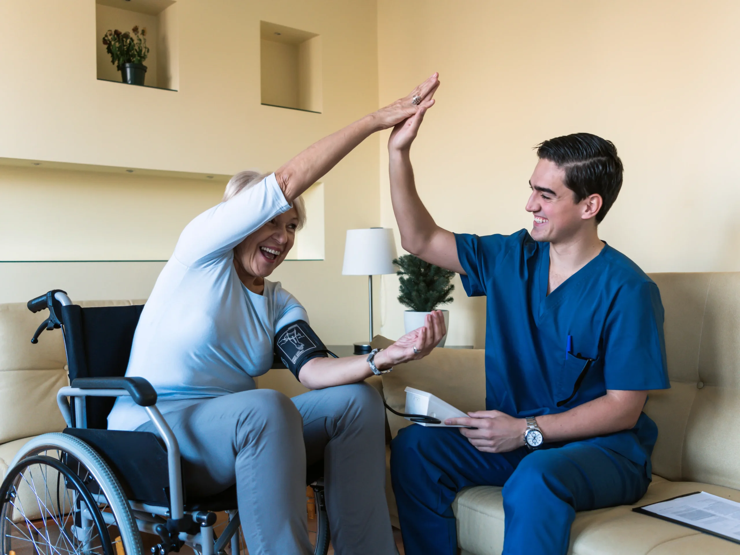woman high-fiving caregiver while taking blood pressure