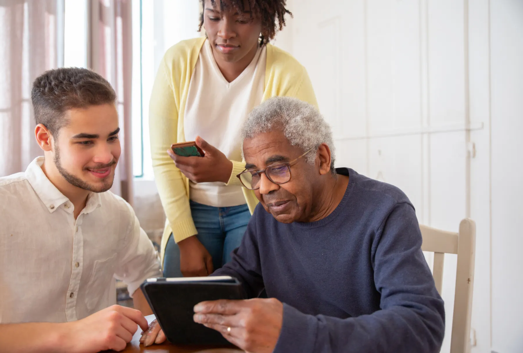 people helping elderly man use a tablet